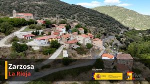 Vista aérea de Zarzosa (La Rioja), con casas agrupadas entre laderas arboladas y una carretera sinuosa.